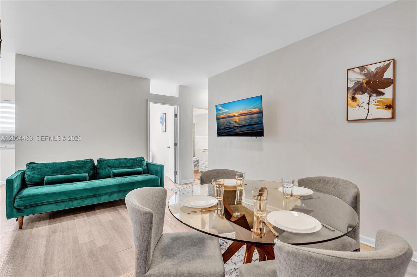 A living and dining area features a green sofa, glass table, and wall-mounted television — 10006 E Bay Harbor Dr # 17, Bay Harbor Islands FL 33154, BAY HARBOR ISLANDS, FL
