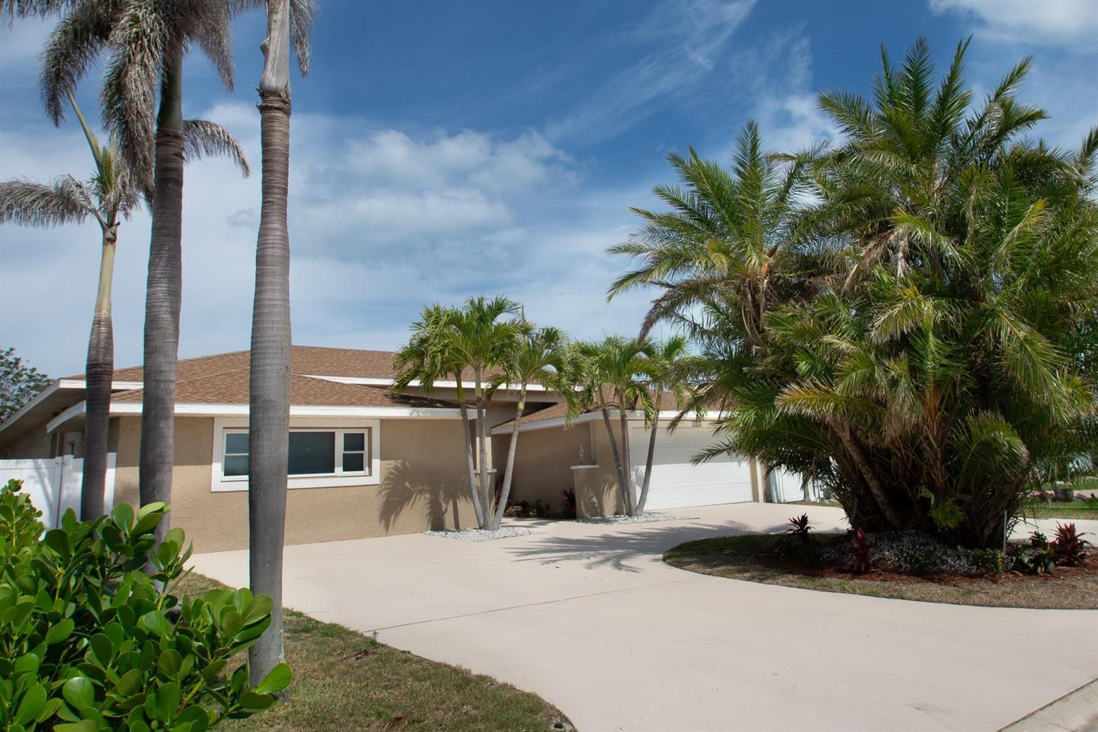 A tan single-story house with a brown shingled roof, a concrete driveway, and several palm trees — 2504 Hibiscus Drive, FL 33786, FL