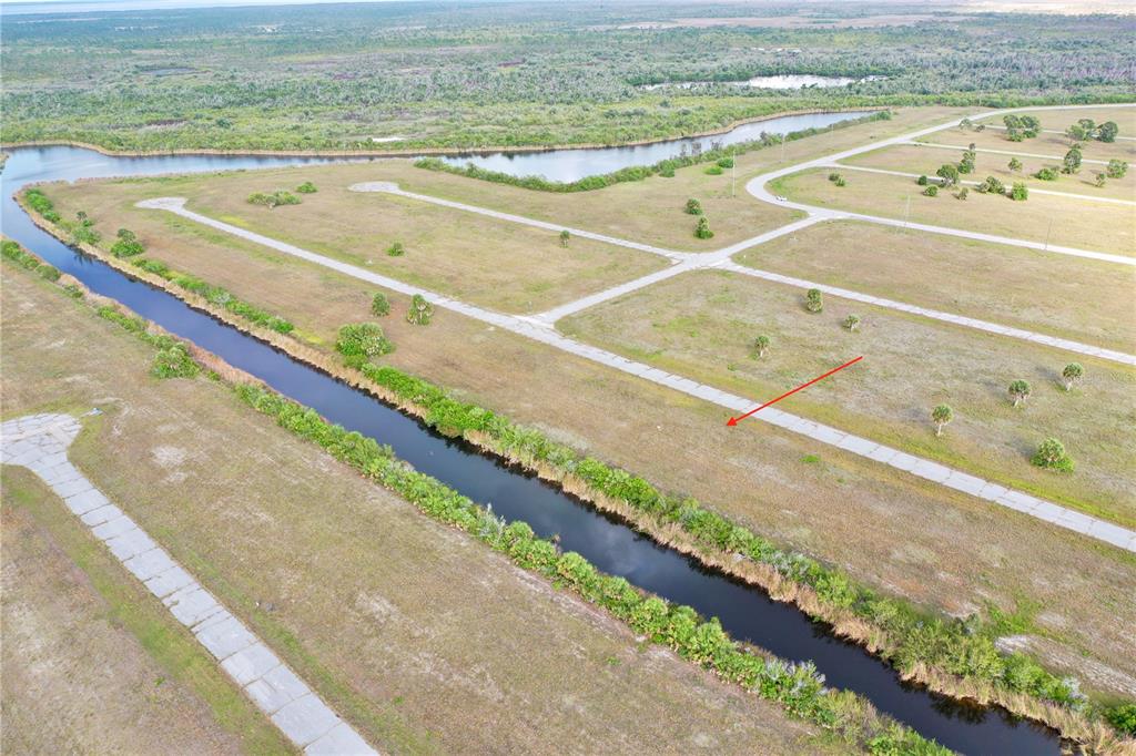 An aerial view shows a vacant lot bordered by a canal and paved roads — 12319 GREENLING WAY, PLACIDA, FL