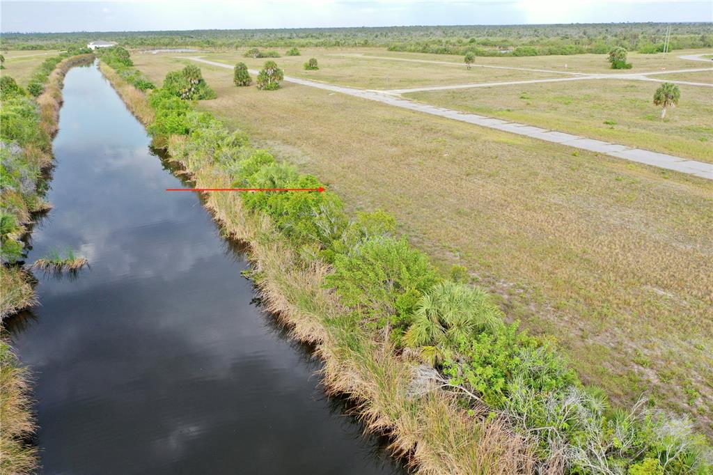 An aerial view shows a canal bordering a vacant lot with paved roads nearby — 12319 GREENLING WAY, PLACIDA, FL