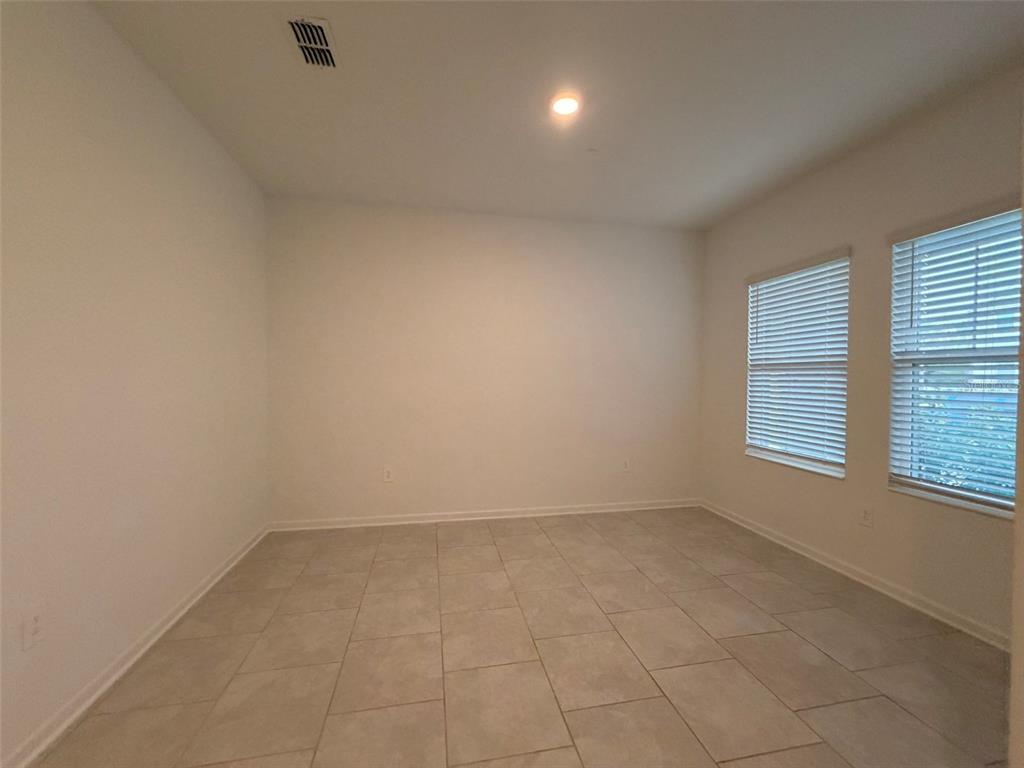 An empty room with light-colored tile flooring, white walls, and two windows with blinds — 2165 SWEET HONEY LANE, APOPKA, FL