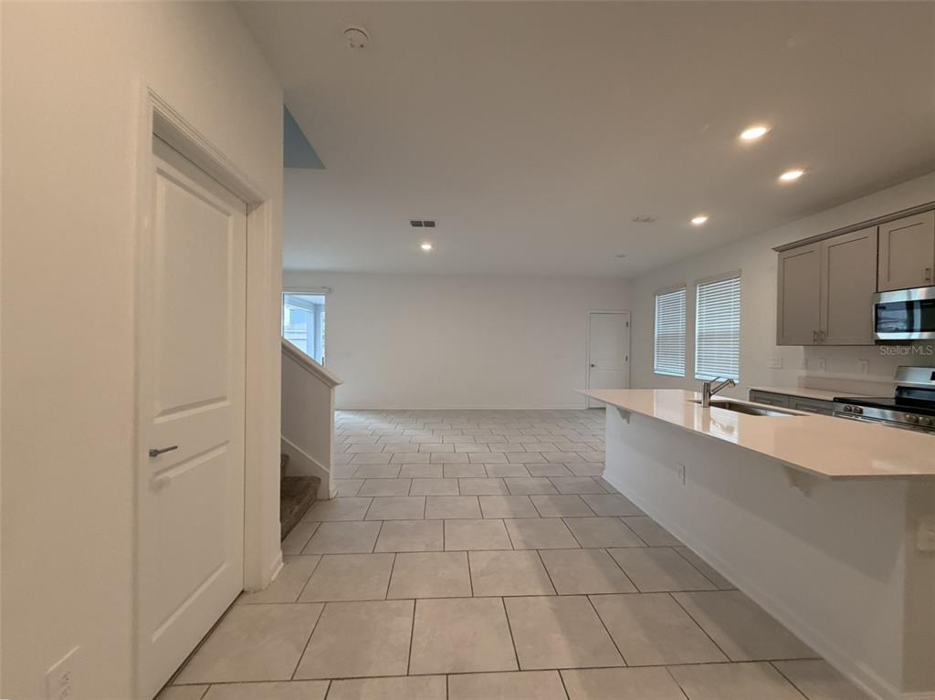 A kitchen with a breakfast bar overlooks an open-concept living area with tiled floors — 2165 SWEET HONEY LANE, APOPKA, FL