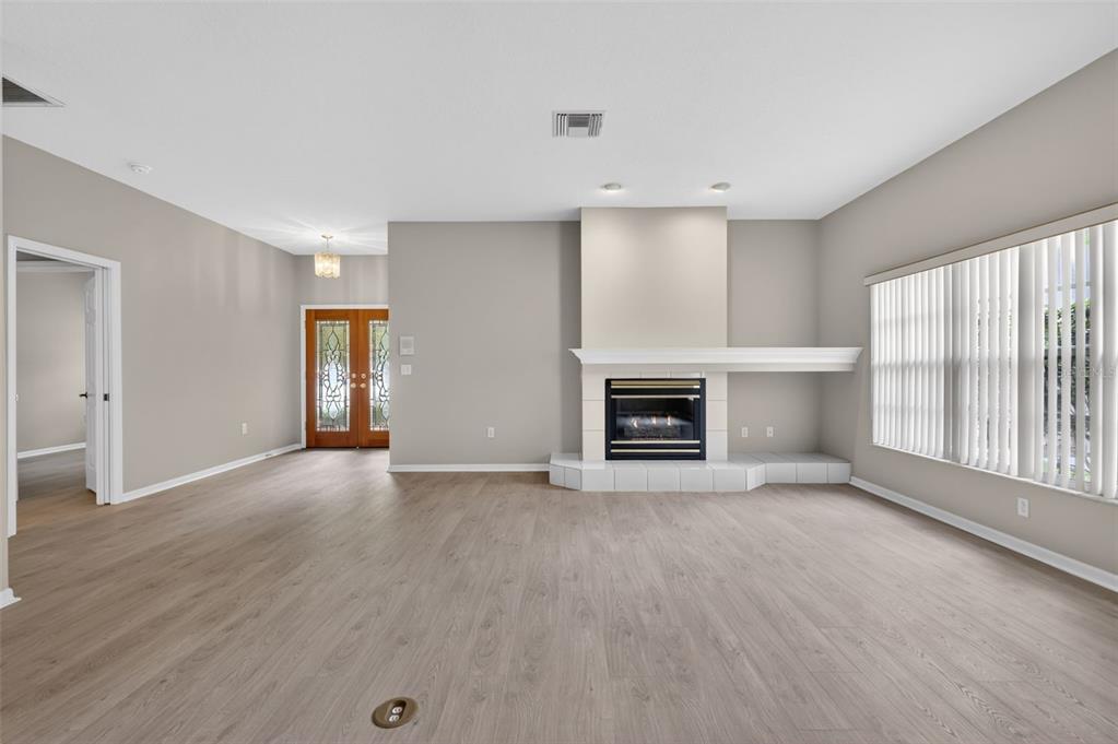A living room features light wood-look flooring, a fireplace with a white hearth, and double doors — 4856 WESTCHESTER COURT, OLDSMAR, FL