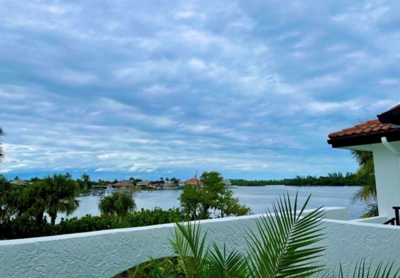 A view of a waterfront bay from a white balcony with palm trees and houses — 6142 SE Landing Way # 11, Stuart FL 34997, STUART, FL