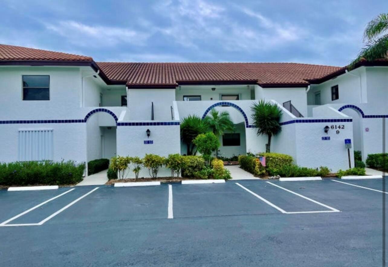 A two-story white stucco apartment building with a tiled roof and a parking lot — 6142 SE Landing Way # 11, Stuart FL 34997, STUART, FL