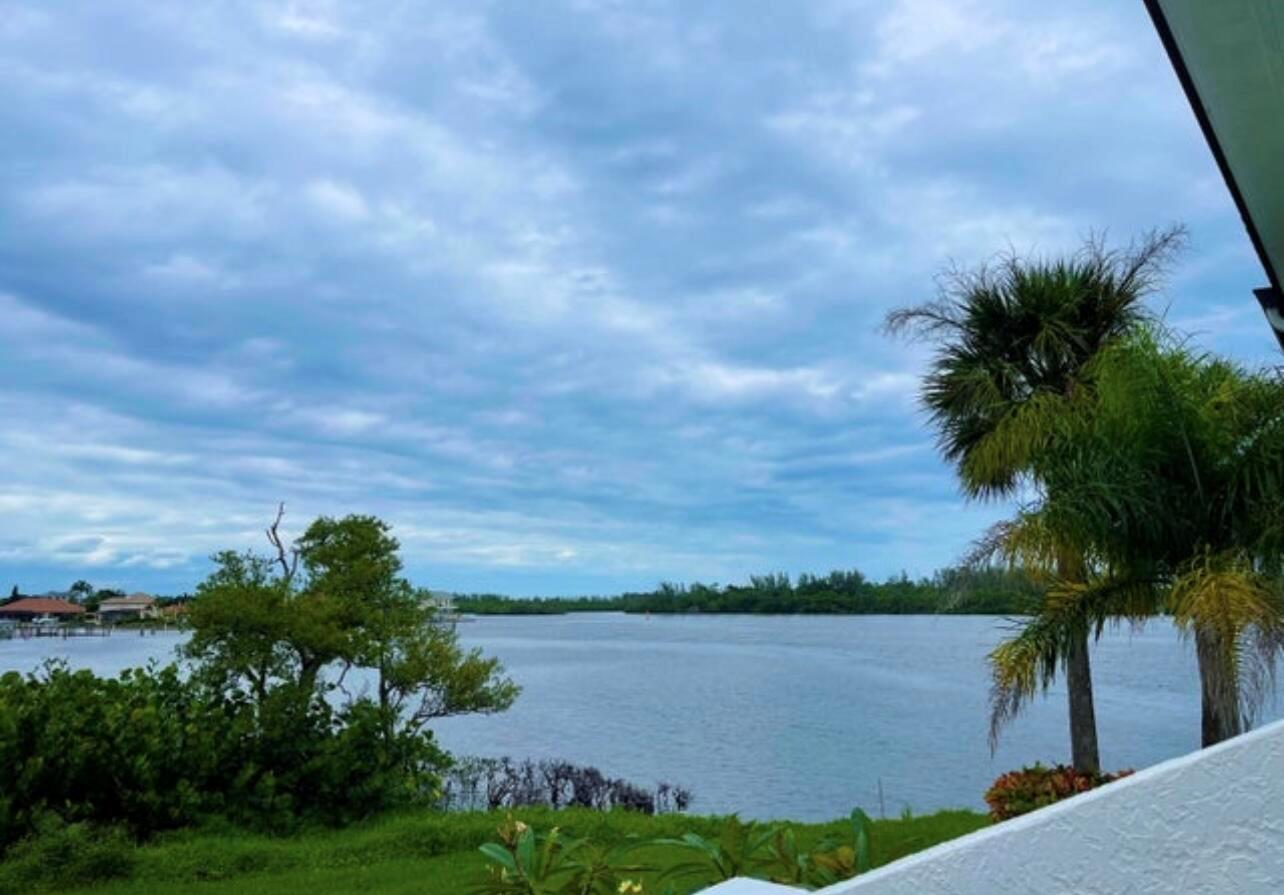 A view of a calm bay with lush greenery and palm trees under a cloudy sky — 6142 SE Landing Way # 11, Stuart FL 34997, STUART, FL