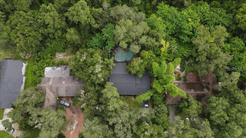 An aerial view shows a house with a swimming pool surrounded by dense green trees — 615 HERMITS TRAIL, ALTAMONTE SPRINGS, FL