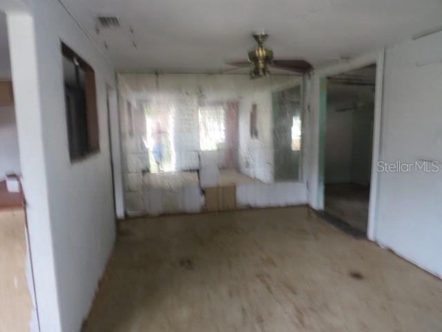 An unfurnished room features a mirrored wall, a ceiling fan, and unfinished flooring — 1785 42ND STREET S, ST PETERSBURG, FL