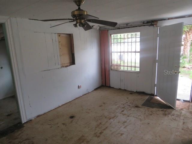 An unfinished room features a ceiling fan, a window with security bars, and an open door — 1785 42ND STREET S, ST PETERSBURG, FL