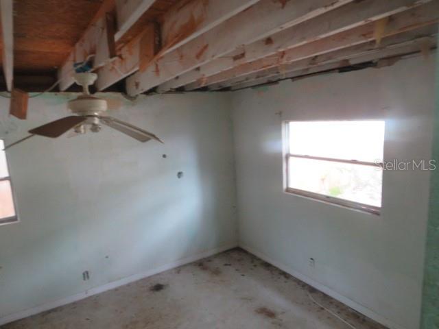 An unfinished room features exposed ceiling joists, a ceiling fan, and white walls with windows — 1785 42ND STREET S, ST PETERSBURG, FL