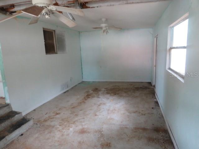 An unfinished room features light blue walls, two ceiling fans, and a concrete floor — 1785 42ND STREET S, ST PETERSBURG, FL