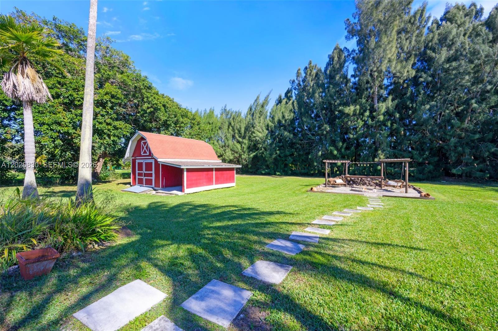 A red barn and a wooden pergola sit on a grassy lawn with stone pavers — 5300 SW 162nd Ave, Southwest Ranches FL 33331, SOUTHWEST RANCHES, FL