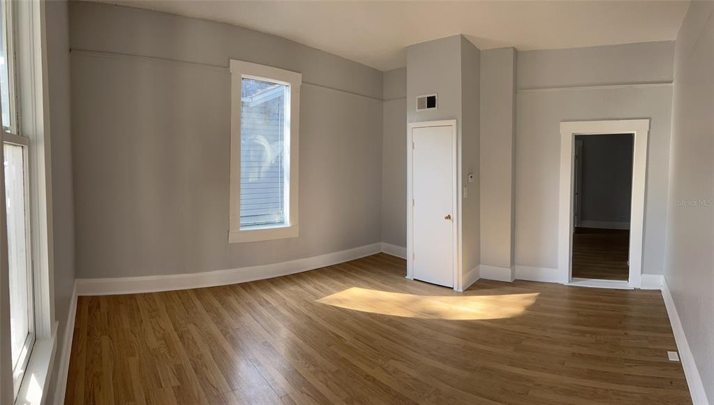 An empty room with light gray walls, wood-look flooring, a window, and two doorways — 901 PENNSYLVANIA AVENUE, LAKELAND, FL
