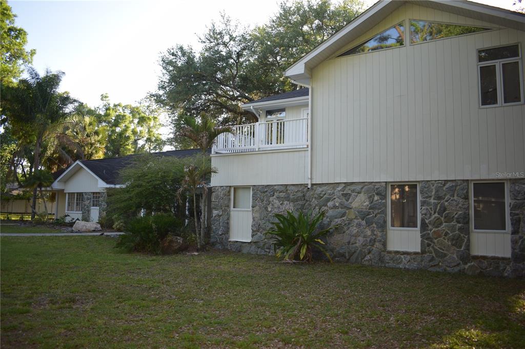 A two-story house features a stone-clad lower level, vertical siding, and an upper-level balcony — 16308 ROCK LAKE DRIVE, ODESSA, FL