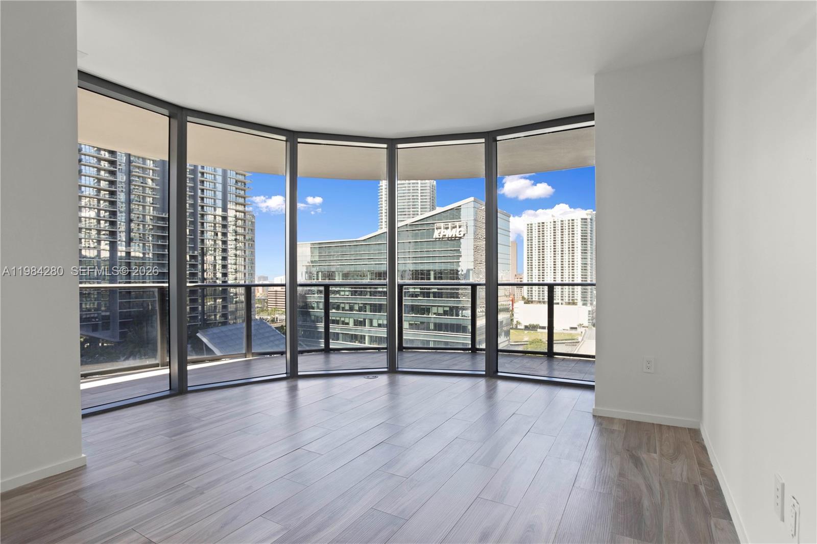 An empty room features light wood-look flooring, white walls, and floor-to-ceiling windows with city views — 801 S Miami Ave # 1609, Miami FL 33130, MIAMI, FL