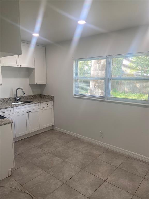 A kitchen with white cabinets, granite countertops, tile flooring, and a window overlooking a yard — 7020 BAYWOOD DRIVE, TAMPA, FL