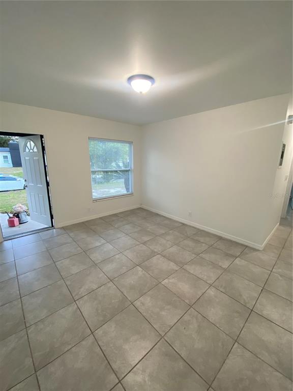 An empty room features light-colored tile flooring, white walls, a single window, and a doorway — 7020 BAYWOOD DRIVE, TAMPA, FL