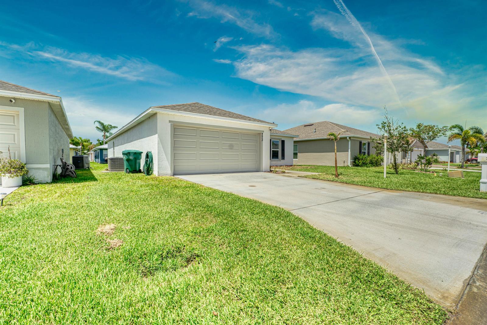 A single-story house with a beige exterior, a two-car garage, and a concrete driveway — 773 SE 25TH Drive, Okeechobee FL 34974, OKEECHOBEE, FL