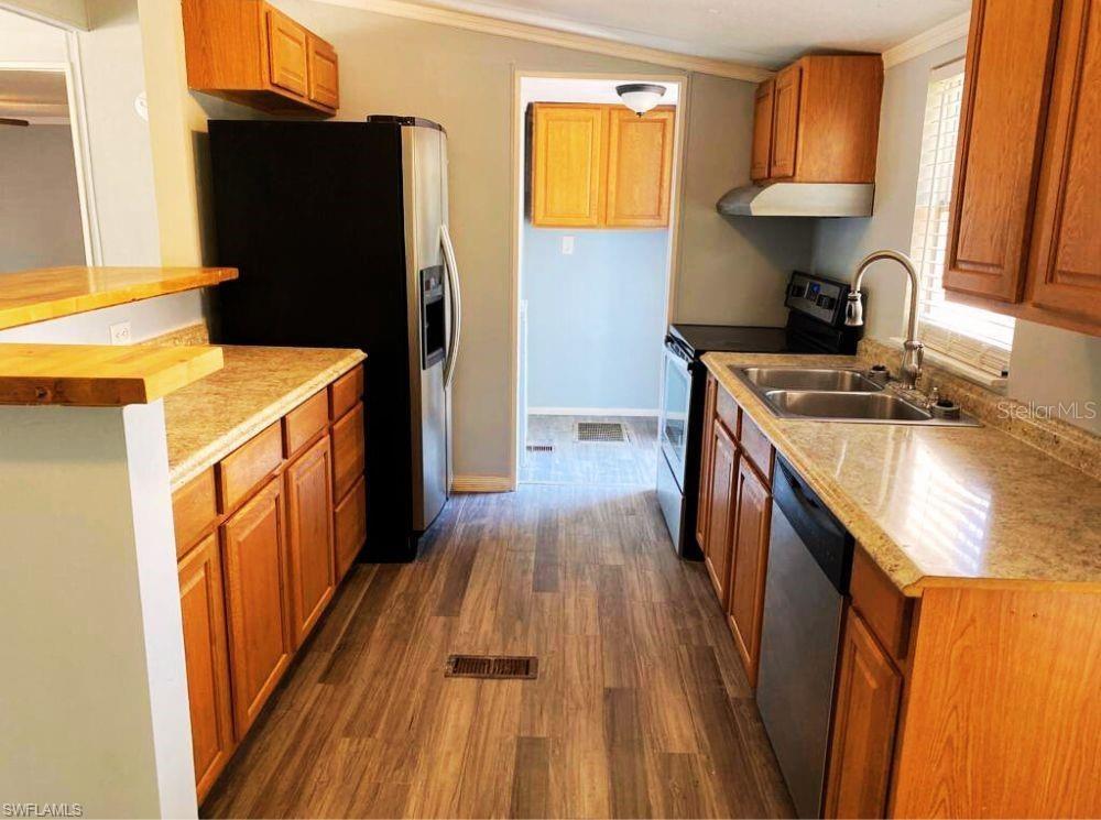 A kitchen features wood cabinets, granite countertops, stainless steel appliances, and wood-look flooring — 1281 RICHMOND AVENUE, CLEWISTON, FL