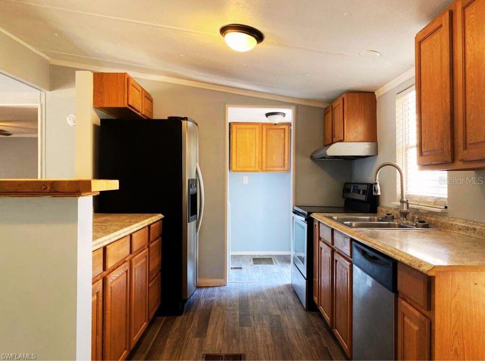 A kitchen with wood cabinets, laminate countertops, stainless steel appliances, and light-colored walls — 1281 RICHMOND AVENUE, CLEWISTON, FL