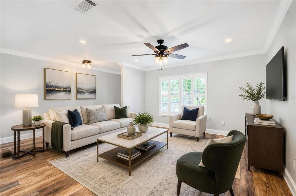 A living room features a beige sofa, two armchairs, a coffee table, and wood flooring — 3817 NW 28TH TERRACE, GAINESVILLE, FL