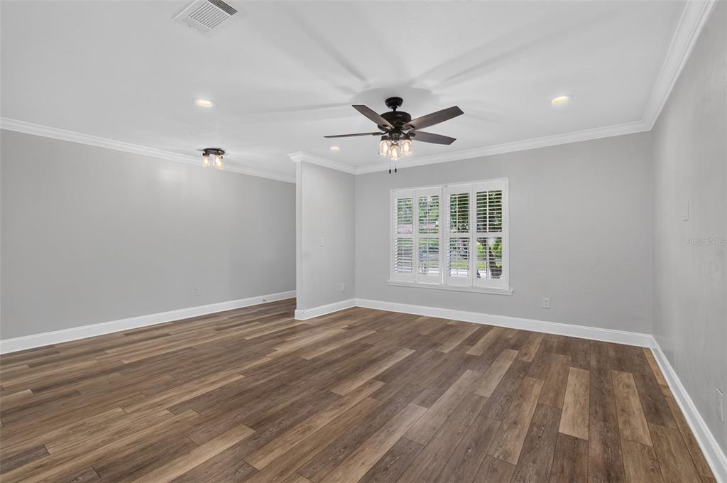 An empty room with light gray walls, wood-look flooring, a ceiling fan, and plantation shutters — 3817 NW 28TH TERRACE, GAINESVILLE, FL