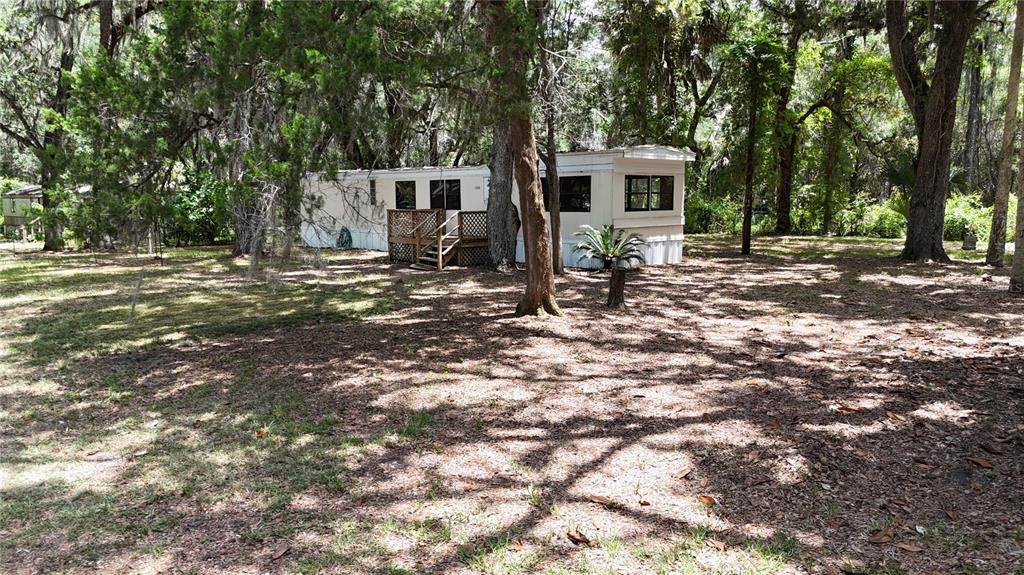 A mobile home sits in a wooded lot with a wooden deck and stairs — 11310 W YELLOW OAK LANE, CRYSTAL RIVER, FL