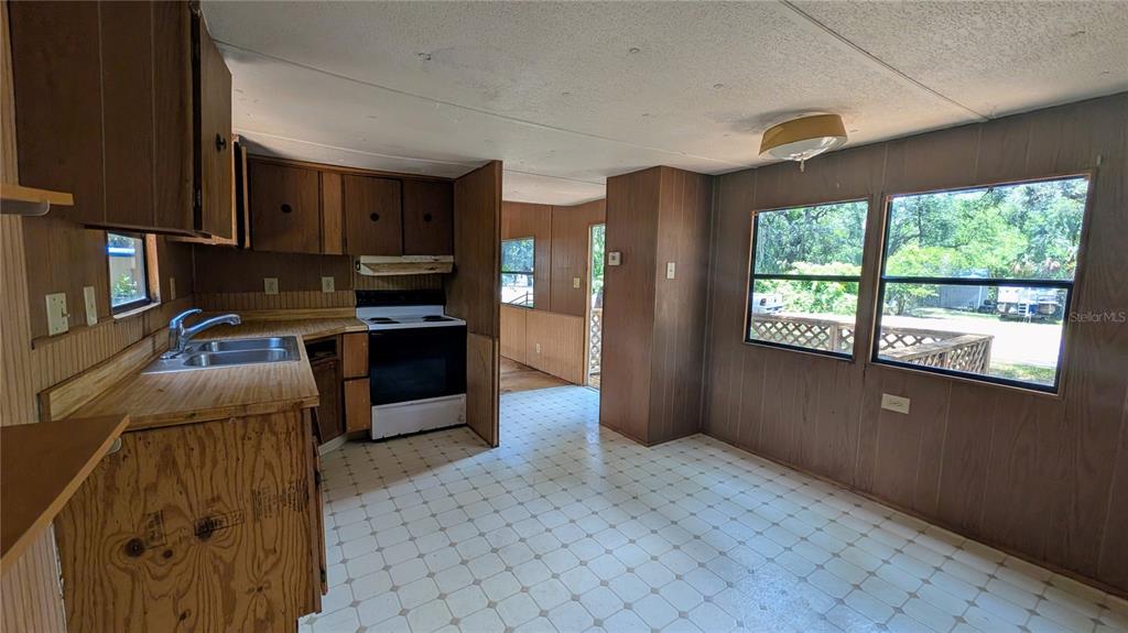 A kitchen and dining area with wood-paneled walls, wood cabinets, and a vinyl floor — 11310 W YELLOW OAK LANE, CRYSTAL RIVER, FL