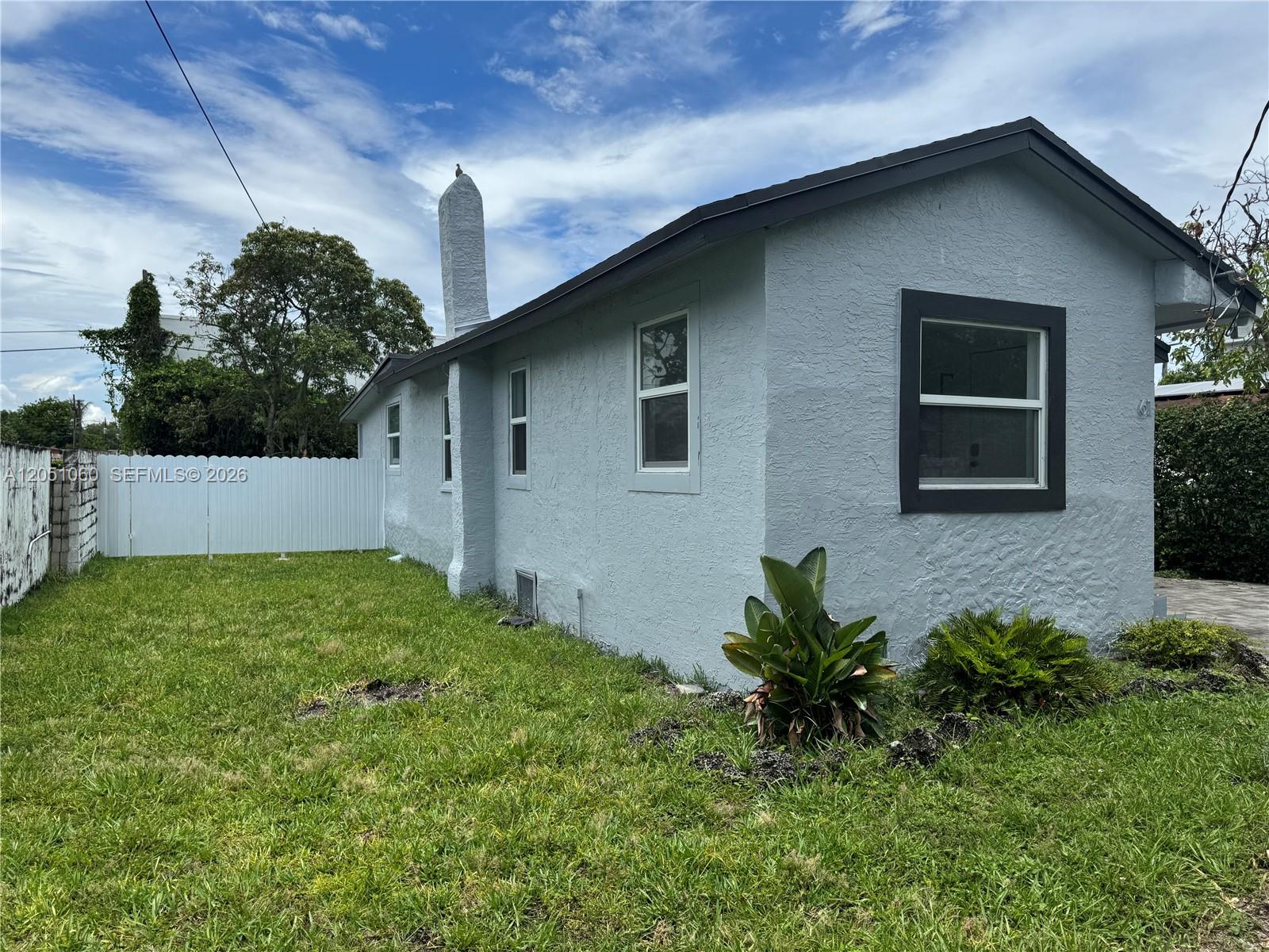 A light blue house with a chimney and a white fence in the backyard — 61 NW 53rd St, Miami FL 33127, MIAMI, FL