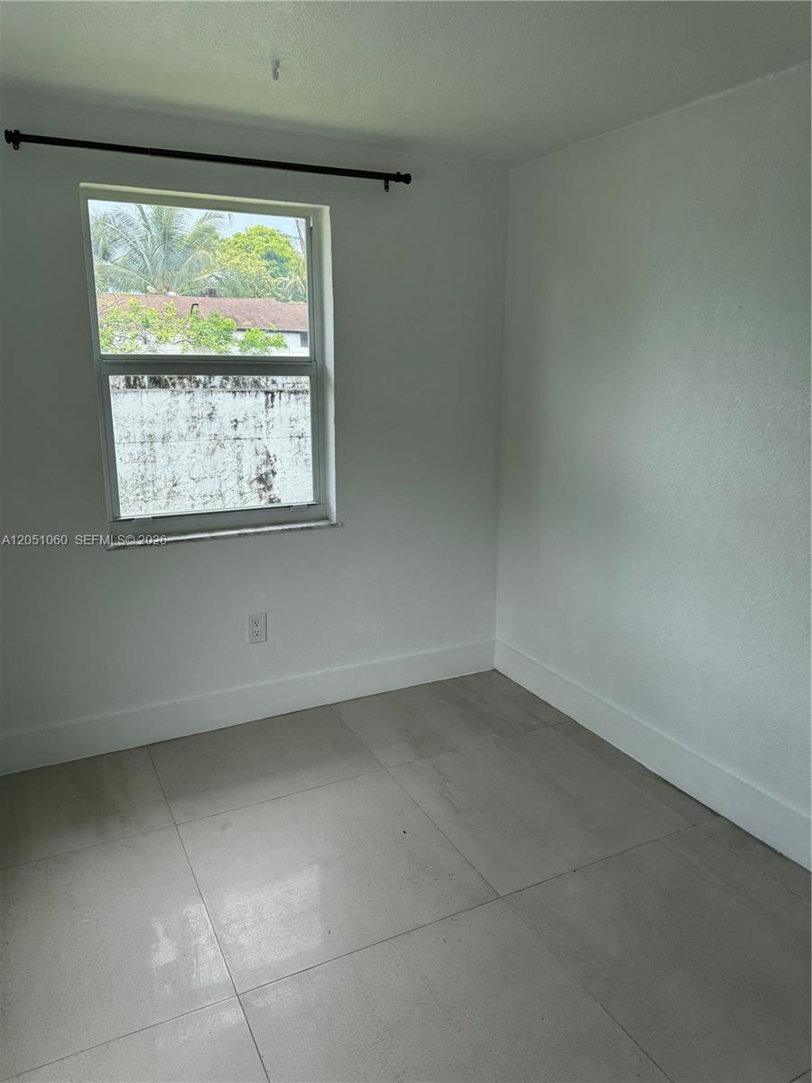 A small, empty room features white walls, light-colored tile flooring, and a single window — 61 NW 53rd St, Miami FL 33127, MIAMI, FL