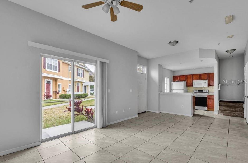 An open-concept living area with tile flooring, a sliding glass door, and an adjacent kitchen — 4012 SANTA MARIA DRIVE UNIT 102, KISSIMMEE, FL