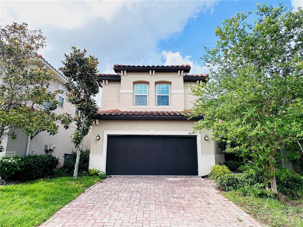 A two-story house with a dark garage door and a brick paver driveway — 10132 GRAND OAK CIRCLE, MADEIRA BEACH, FL