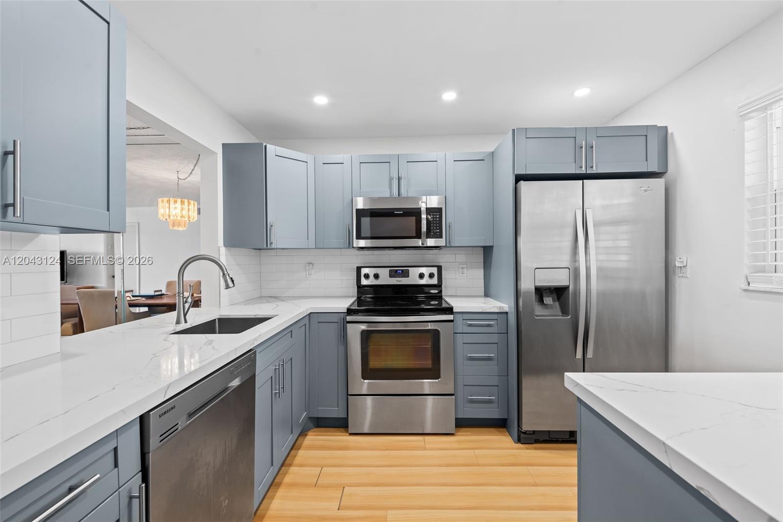 A kitchen features blue cabinets, stainless steel appliances, and white countertops with a backsplash — 4025 N Nob Hill Rd # 301, Sunrise FL 33351, SUNRISE, FL