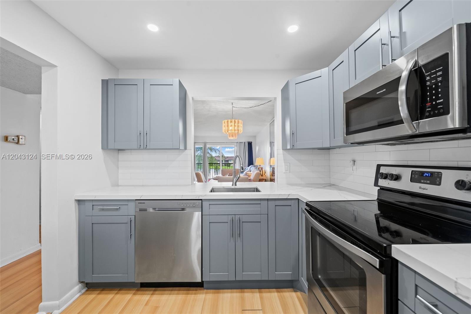A kitchen features blue cabinets, stainless steel appliances, white countertops, and a subway tile backsplash — 4025 N Nob Hill Rd # 301, Sunrise FL 33351, SUNRISE, FL