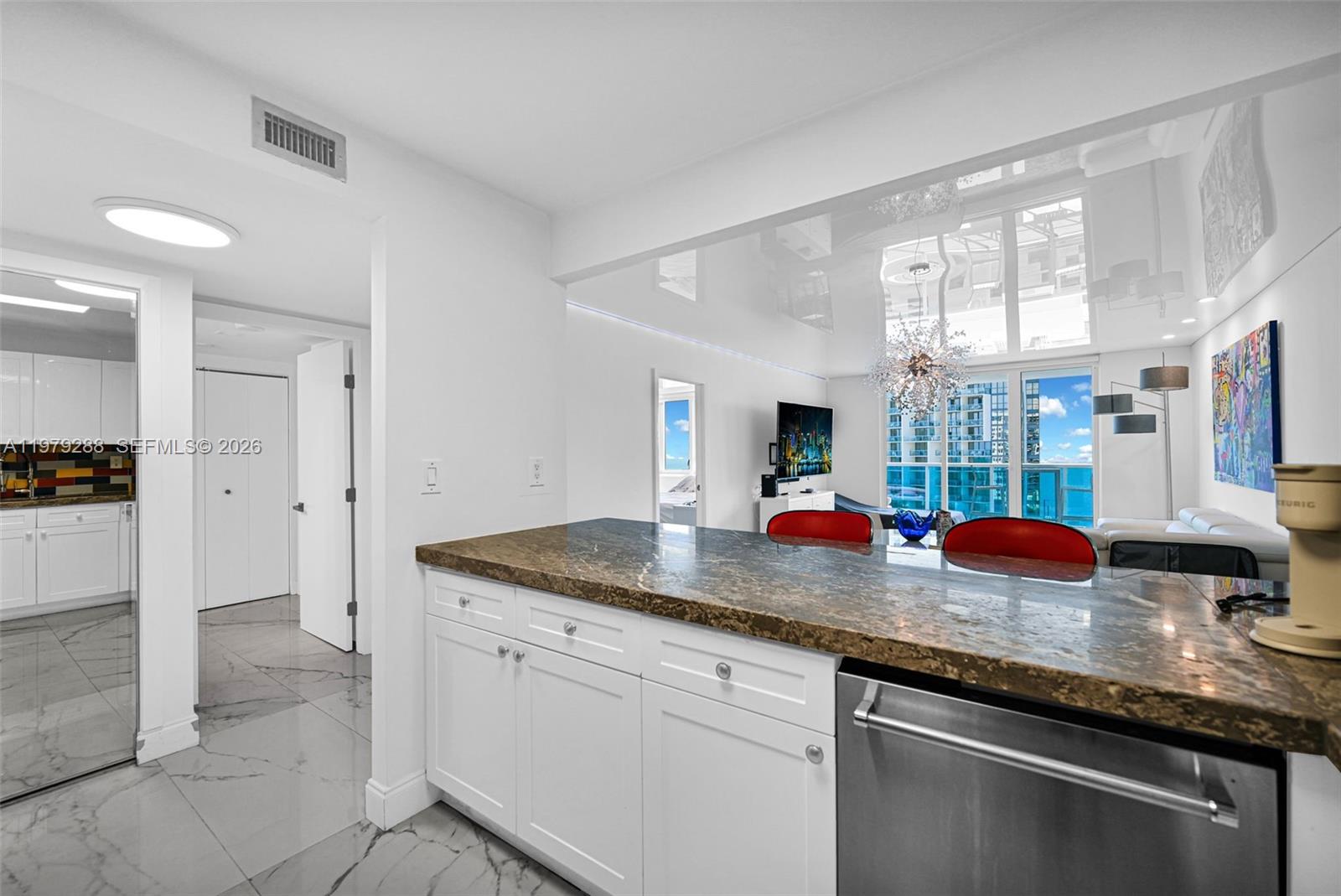 A kitchen island with a granite countertop overlooks a living area with floor-to-ceiling windows — 2301 Collins Ave # 1204, Miami Beach FL 33139, MIAMI BEACH, FL
