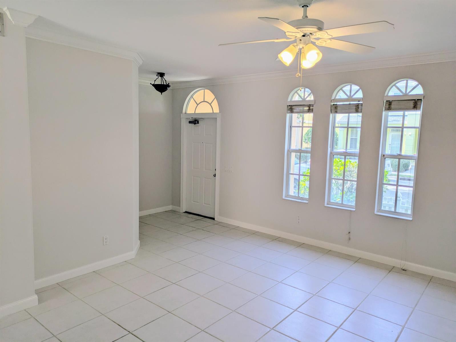 An empty room with white tile floors, a ceiling fan, and three arched windows — 143 Middlebury Drive, Jupiter FL 33458, JUPITER, FL