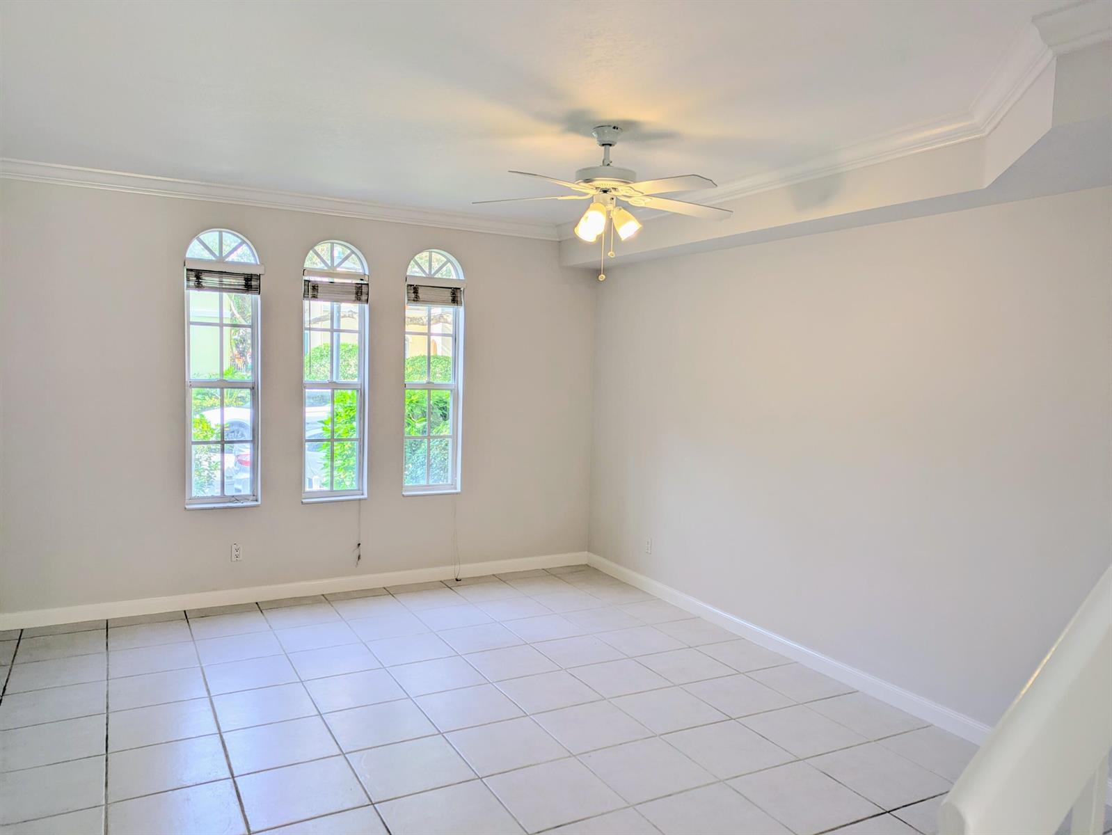 An empty room with light-colored tile floors, a ceiling fan, and three arched windows — 143 Middlebury Drive, Jupiter FL 33458, JUPITER, FL