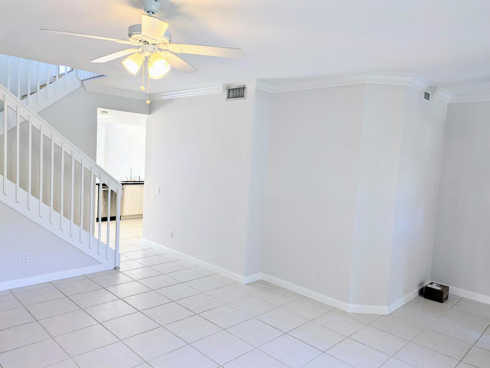 An interior view of a room with white tile floors, a staircase, and a ceiling fan — 143 Middlebury Drive, Jupiter FL 33458, JUPITER, FL