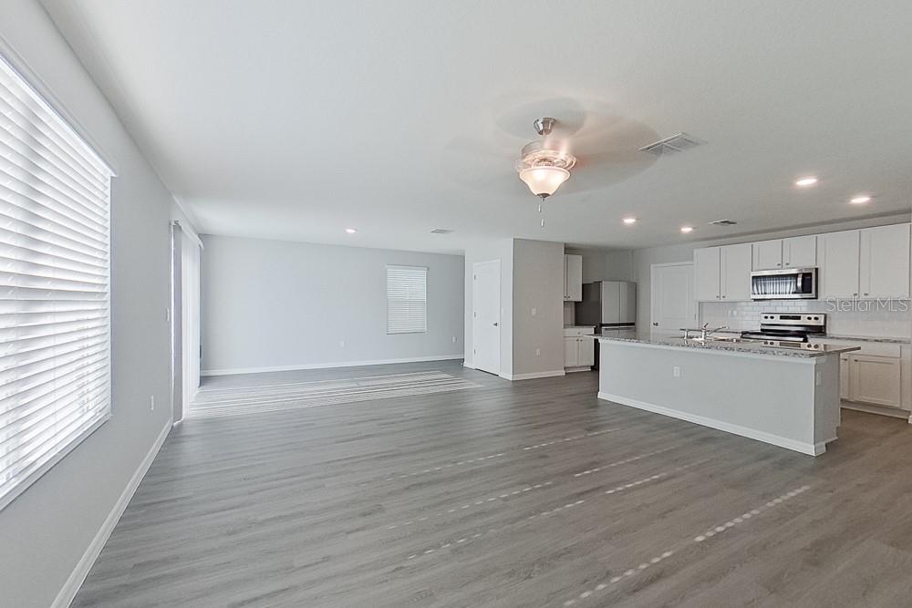 An open-concept kitchen and living area feature light gray walls, wood-look flooring, and white cabinetry — 8614 SW 43RD TERRACE, OCALA, FL