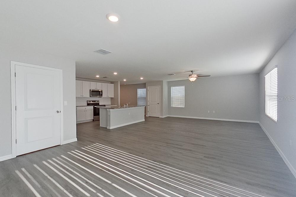 An open-concept living area features gray wood-look flooring, a kitchen with white cabinets, and an island — 8614 SW 43RD TERRACE, OCALA, FL