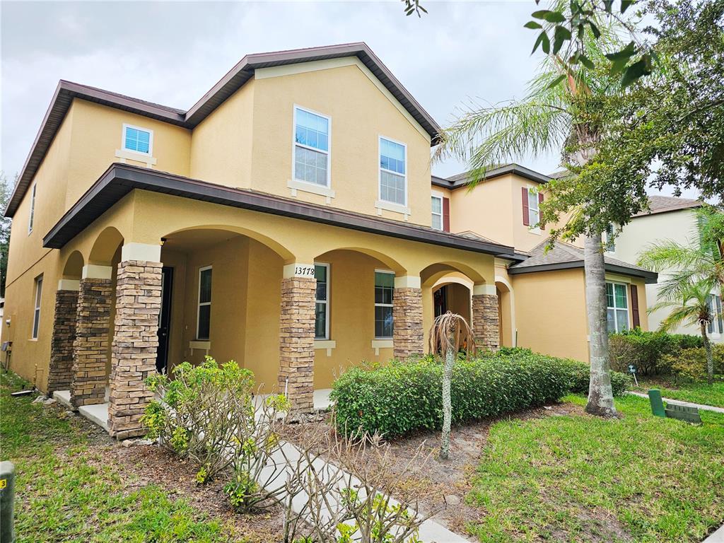 A two-story house with a tan stucco exterior, stone-accented columns, and a covered front porch — 13778 SUMMERPORT TRAIL LOOP, WINDERMERE, FL