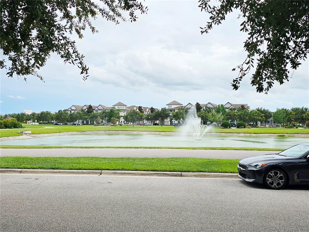 A dark car is parked on a street overlooking a pond with a fountain — 13778 SUMMERPORT TRAIL LOOP, WINDERMERE, FL