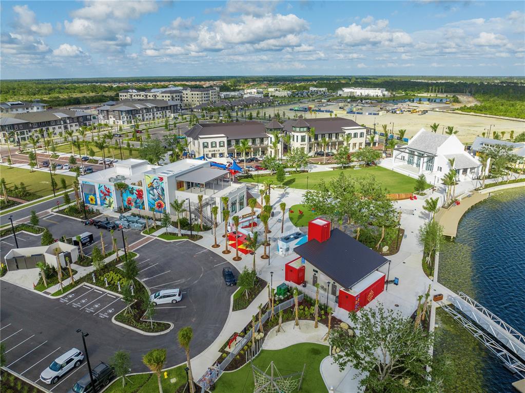 An aerial view shows a modern commercial plaza with parking, a lake, and surrounding buildings — Lot 26, GLOBE TERRACE, NORTH PORT, FL