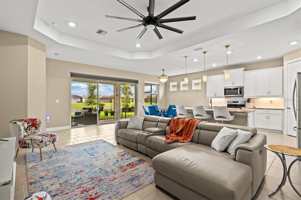 A spacious open-concept living room and kitchen featuring a large sectional sofa and tile flooring — 1656 REMINGTON TRACE DRIVE, PORT CHARLOTTE, FL