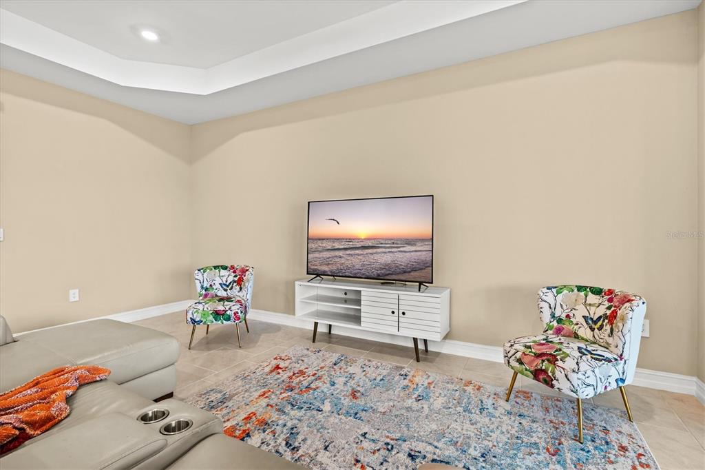 A living room features a television on a white console, two floral chairs, and a rug — 1656 REMINGTON TRACE DRIVE, PORT CHARLOTTE, FL