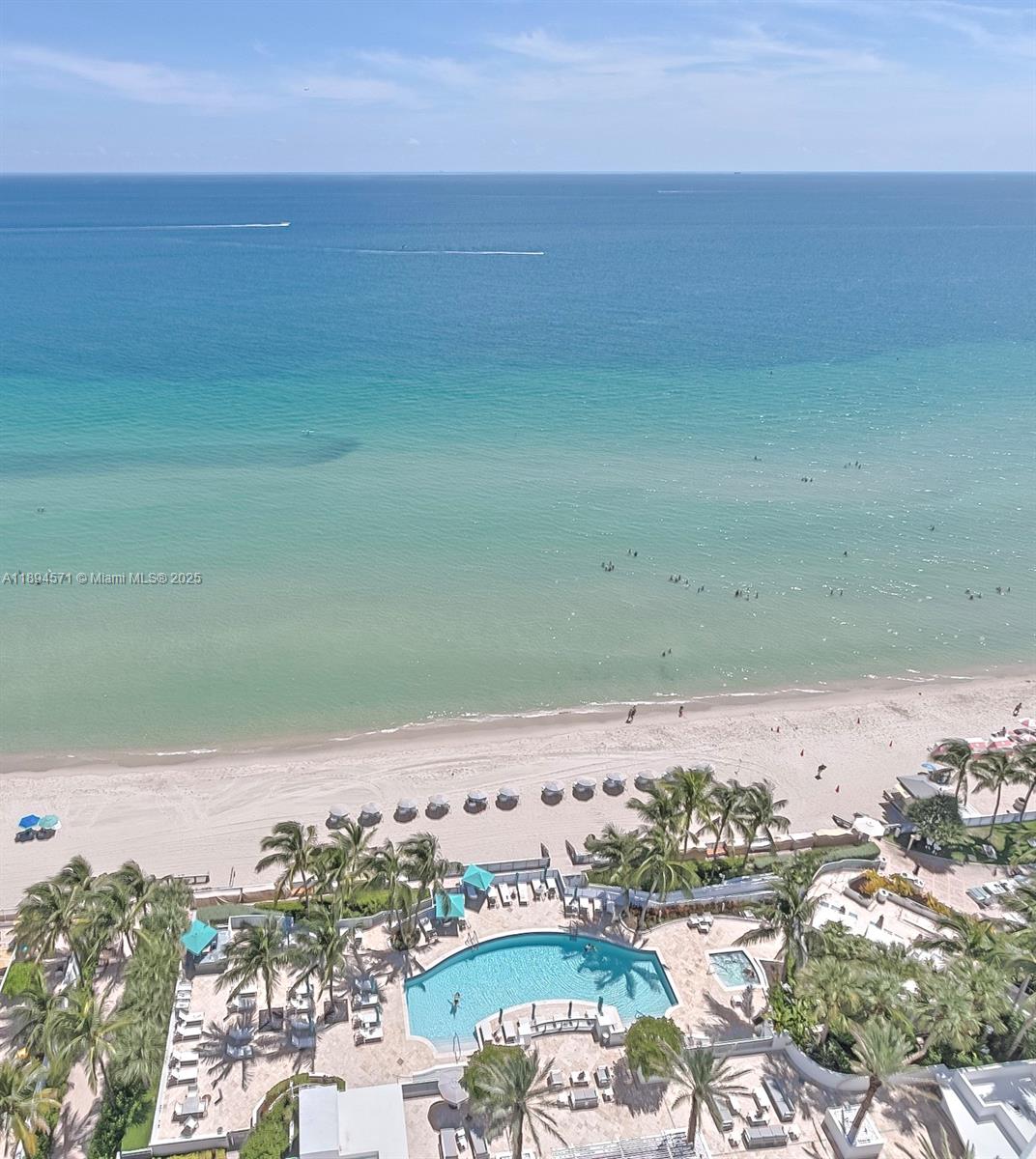 An aerial view shows a swimming pool, palm trees, sandy beach, and the ocean — 3535 S OCEAN DR # 2102, Hollywood FL 33019, HOLLYWOOD, FL