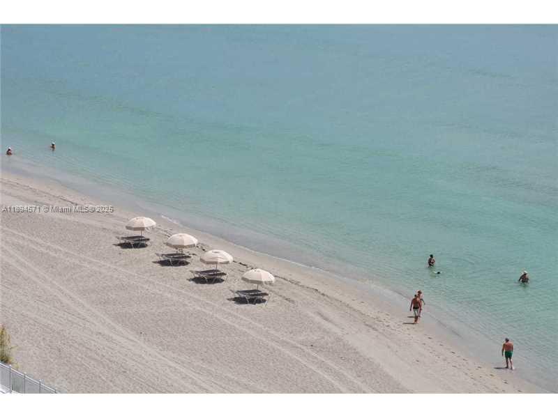 An aerial view of a sandy beach with several umbrellas and people swimming in the ocean — 3535 S OCEAN DR # 2102, Hollywood FL 33019, HOLLYWOOD, FL