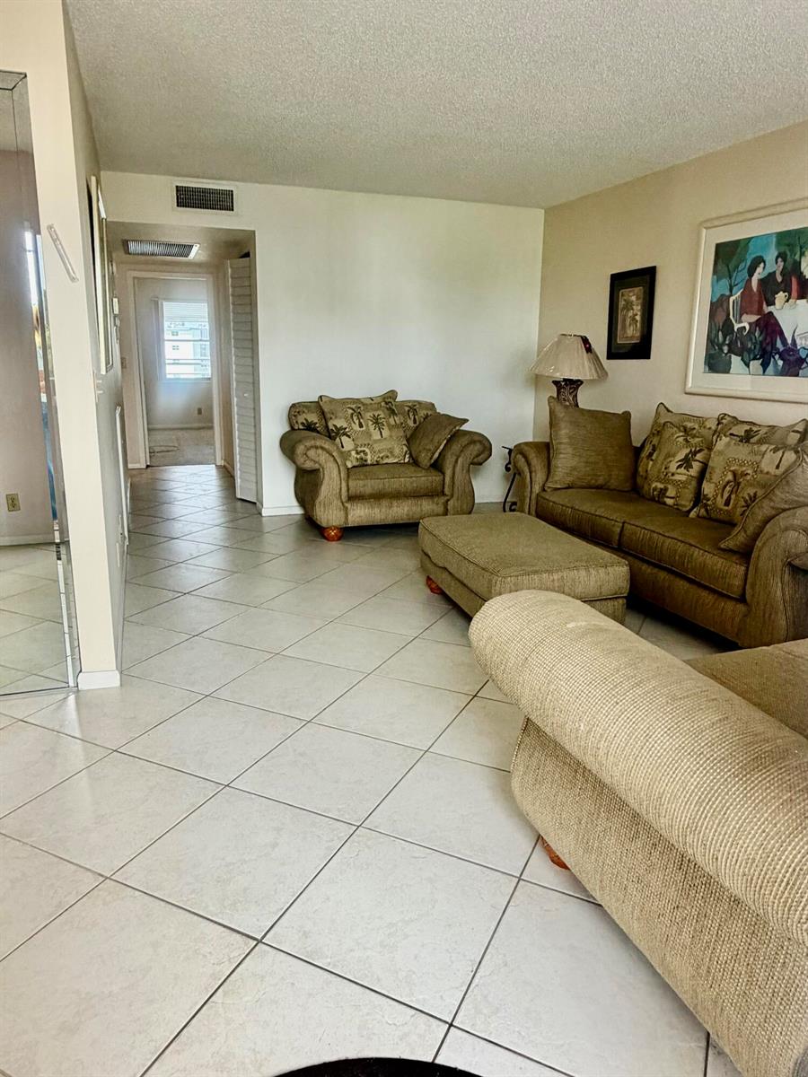 A living room features light-colored tile flooring, beige furniture, and a hallway leading to another room — 3035 Rexford, Boca Raton FL 33434, BOCA RATON, FL