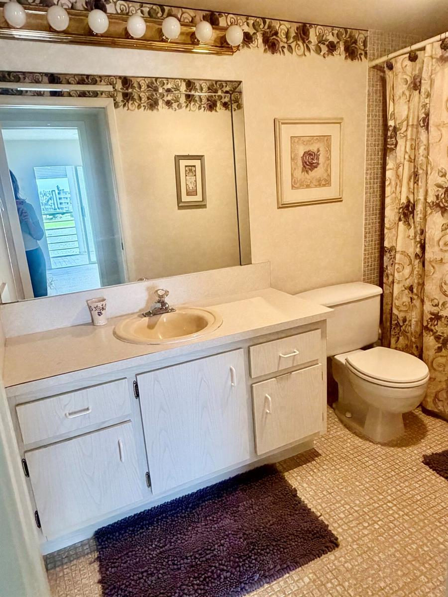 A bathroom features a vanity with a beige sink, a mirror, and a floral shower curtain — 3035 Rexford, Boca Raton FL 33434, BOCA RATON, FL
