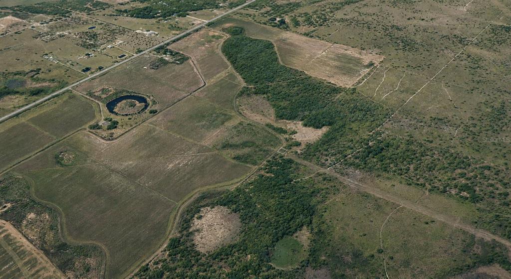 An aerial view of a large, rural property featuring open fields, wooded areas, and a pond — 60 E STREET, LAKE WALES, FL